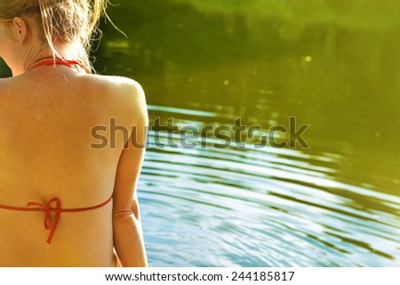 Back view portrait of a beautiful relaxed woman on the sunny beach with blue water background