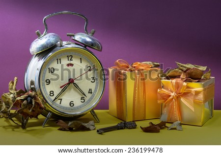 Still life with broken alarm clock, vintage key, dead rose, gift boxes, colorful background.