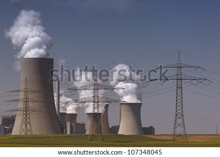 Brown coal power plant with huge cooling towers and steam and powerlines