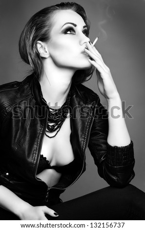 a portrait of beautiful sexual redheaded girl is in a black leather jacket, smoking a cigarette