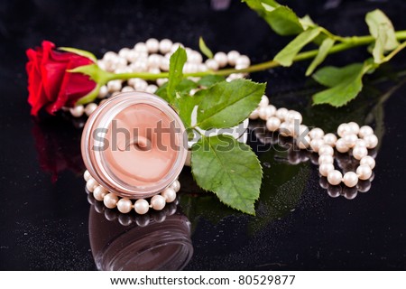 Beige liquid in the round glasses box with pearls,flowers and dropes water.
