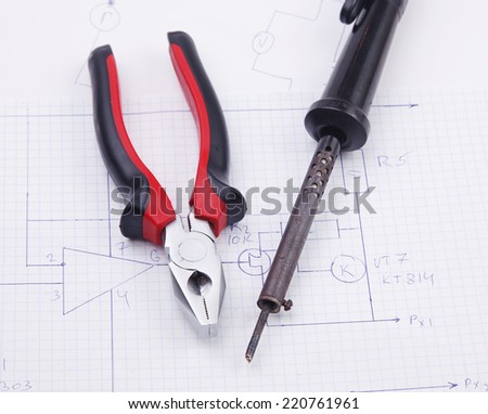 Pliers and  soldering iron on a background of the electric scheme