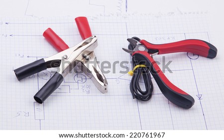 Metal nippers and electric clamps on a background of the electric scheme