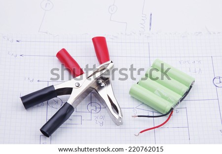 Electric clamps and battery on a background of the electric scheme