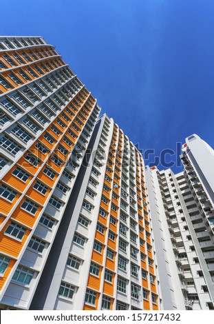 A vertical low angle shot of a new colorful high rise apartment against the sky.