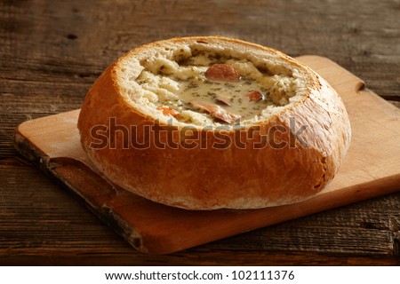 Traditional Polish soup made from fermented rye flour with sausages, eggs, meat and vegetables served in bowl made of bread