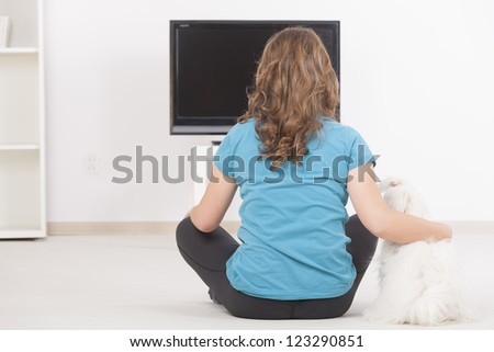 Woman and cute white maltese dog watching TV together at home