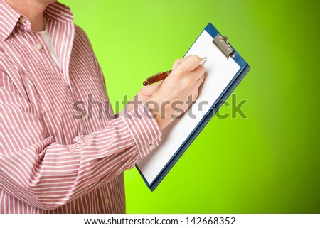 Man holding a clipboard and taking a notes with pen