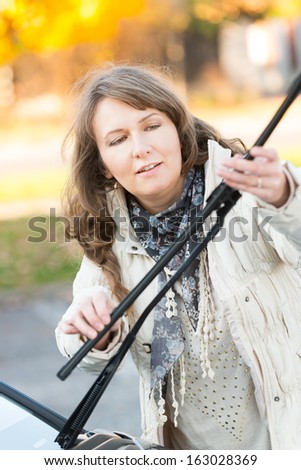 Beautiful woman picking up windscreen wiper and checking it