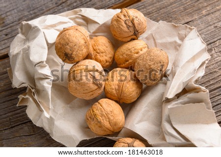 Pile of walnuts in paper bag on wooden board