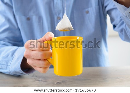 Tea bag with mug in hand