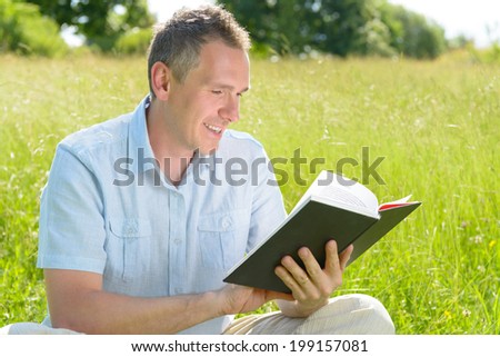 Handsome man reading book outside