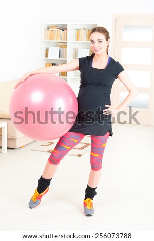 Young pregnant woman exercising with gym ball at home