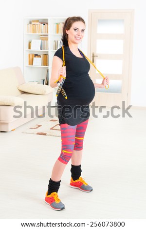 Young pregnant woman exercising with skipping rope or jump rope at home