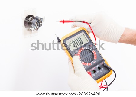 Electrician checking socket voltage with digital multimeter