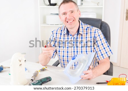 Smiling man repairing iron at home appliance service workshop