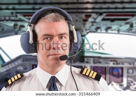 Airline pilot wearing uniform with epaulettes and headset, on board passenger aircraft.