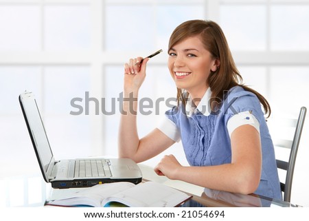 Woman in office or school or home working with papers and laptop