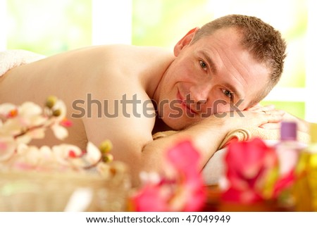 Man resting in sunny spa salon laying with flowers