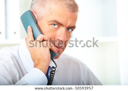 Mature businessman in office with landline phone