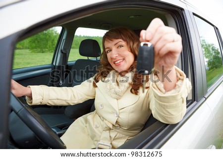 Beautiful woman sitting in a car and showing keys out the window