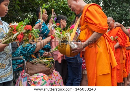 SARABURI,THAILAND-JULY 17:Many People Give Flowers to Buddhist Monks for alms in The Tak Bat Dok Mai (give flowers to monk) Ceremony at Phrabuddhabat Temple on July 17,2011 in Saraburi,Thailand.