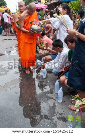 SARABURI, THAILAND-JULY 22:Unidentified people offer flowers to unidentified monks in the row during Buddhist ceremony at Phrabuddhabat temple on July 22, 2013 in Saraburi, Thailand.
