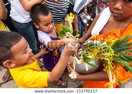 SARABURI, THAILAND-JULY 22:An unidentified child offers flowers to Buddhist monk ceremony at Phrabuddhabat temple on July 22, 2013 in Saraburi, Thailand.