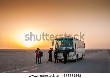 DUNHUANG,CHINA-OCTOBER 17: tourist bus stop with sunrise on the road to  Yadan landforms on October 17,2013 in Dunhuang ,Gansu,China.Yadan Landforms is physiognomy landscape.