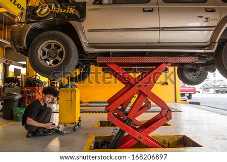 BANGKOK-DEC 06:The car mechanic change motor oil with car raised on lifts at B-Quik garage on December 06,2013 in Bangkok,Thailand.