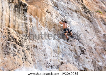 KRABI, THAILAND - MARCH 29, 2014: Rock climbers climbing on Railay beach in Krabi, Thailand. Railay beach is one of the most popular rock climbing locations in Asia.