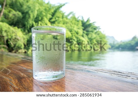 Glass of cold mineral water on the table of the natural background