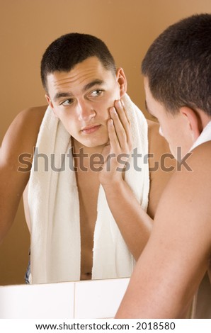 reflexion of young man in the bathroom\'s mirror after shaving