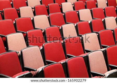 Rows of red velvet theater seats in a modern theater.