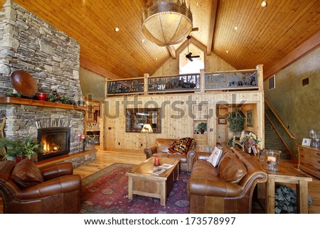 Island Park, Idaho, USA 28 Oct. 2009 The interior of a modern log cabin featuring a stone fireplace, pine paneling, and comfortable furniture.