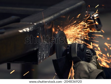 Electric grinding wheel smoothing the surface of a steel structure in factory