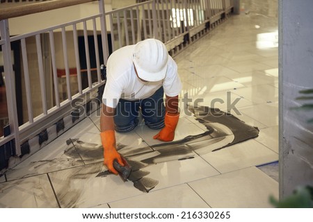 Boise, ID Aug 15, 2008 A tile worker grouting the new ceramic tile floor in a commercial retail mall.  He is depicted observing all safe workplace practices.