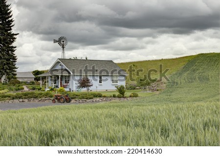 Palouse, Washington, USA 13 June, 2014 A farm house with a tractor and windmill in the rolling farm fields in Palouse Washington