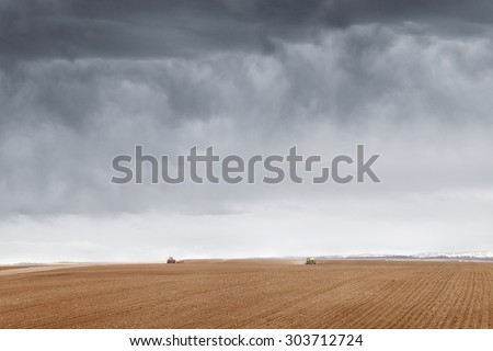 Rexburg, Idaho, USA Apr. 22, 2013 Farm machinery planting rows of wheat on a windy spring day in the fertile farm fields of Idaho.