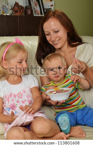 Young mother with her children at home  eating candy