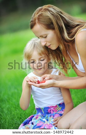 happy smiling little girl with mother eat raspberries