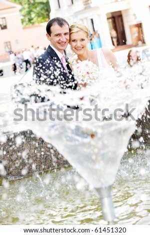 bride and groom stand near  fountain