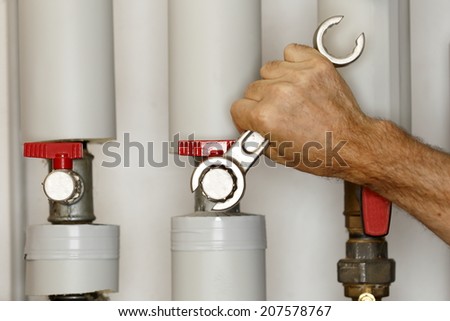 man is working on heating pipes with wrench