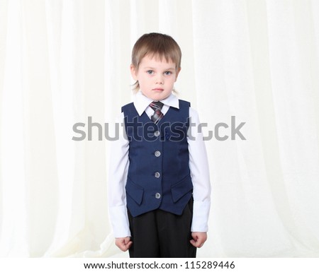 Portrait of smart little blond boy in suit at home