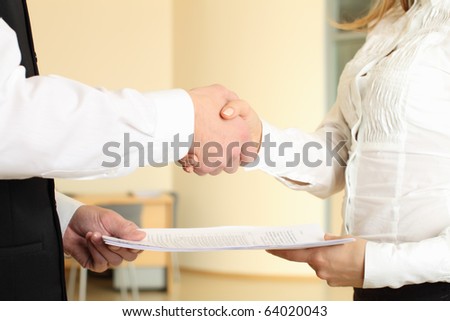 Man and woman shaking hands in office and giving papers
