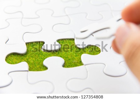 hand holding a puzzle piece, green space concept