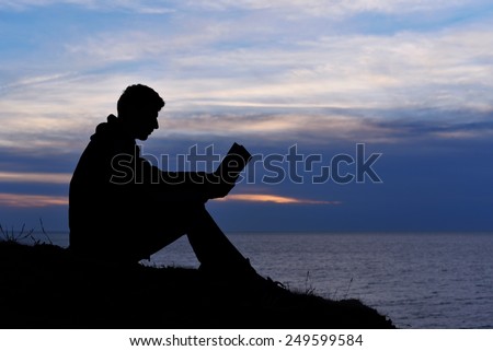 Silhouette of man reading in the sunset light, sea, ocean, nature