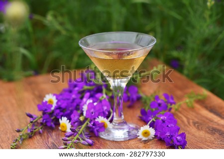 glass cocktail on wooden table in the garden with flowers