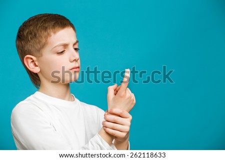 Boy looking at white adhesive plaster on his thumb
