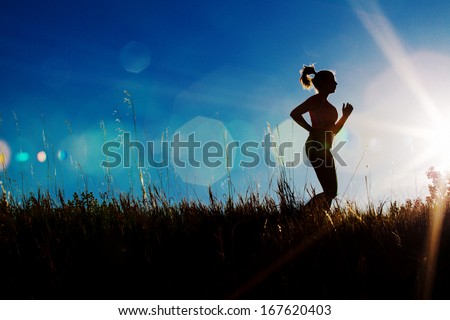 Silhouette of a female jogger with sun flare